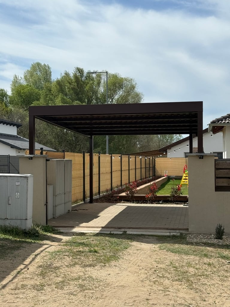 Modern backyard pergola with black metal frame and wooden privacy fencing, adjacent to residential homes under cloudy sky.